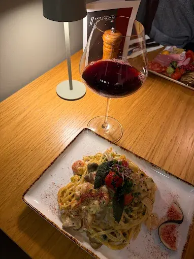 Tagliatelle mit Garnelen, dazu ein Glas Rotwein am Tisch