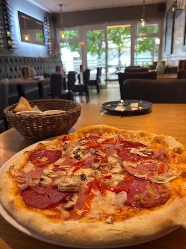 Frisch gebackene Pizza auf dem Tisch im Restaurant, im Hintergrund der Gastraum