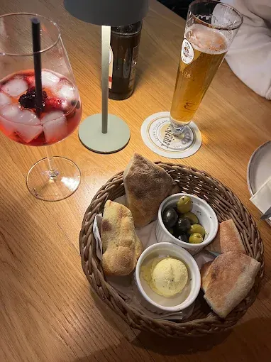 Brotkorb mit Oliven und Butter, dazu ein Aperitif am Tisch